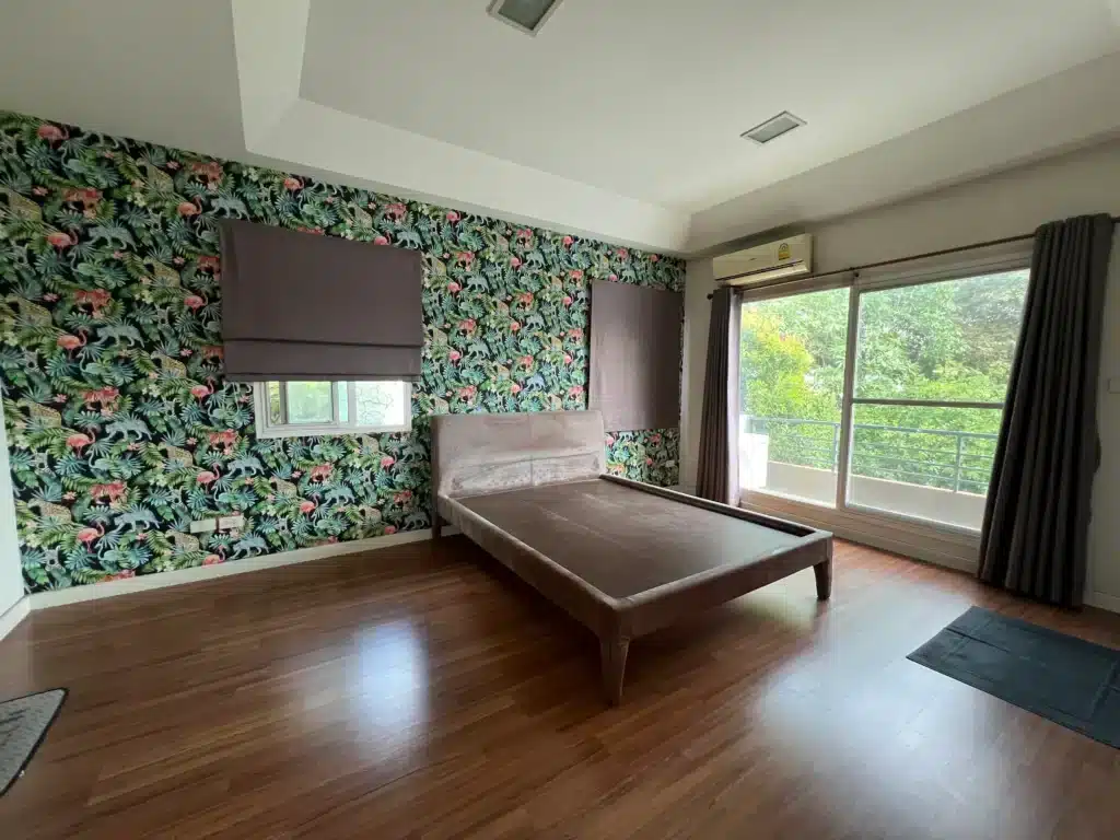 ภาพห้องนอนใหญ่ที่แสดงให้เห็นถึงความกว้างขวาง งานพื้นไม้ที่สมบูรณ์ ผนังตกแต่ง และประตูกระจกบานใหญ่ที่เชื่อมสู่ระเบียง เพื่อสร้างความประทับใจสูงสุดให้กับผู้ที่กำลังมองหาพื้นที่พักผ่อนที่สมบูรณ์แบบ